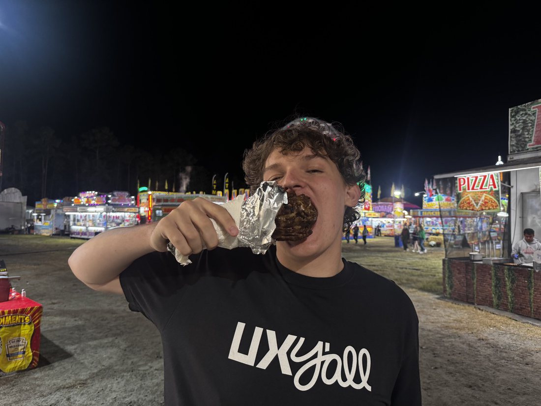 Brayden eating a turkey leg at a fair at night