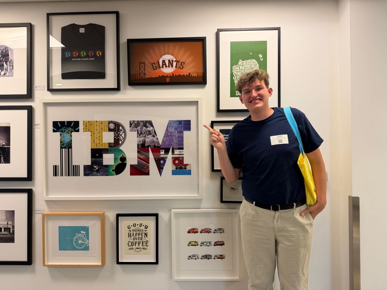 Brayden pointing at a collaged IBM logo on an office gallery wall, wearing a visitor badge