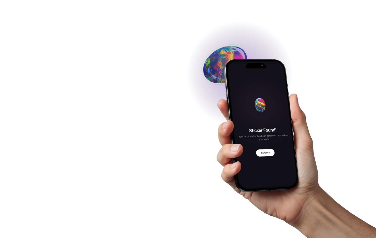 A hand holding a phone showing a Sticker Found screen, with a physical focus sticker beside it